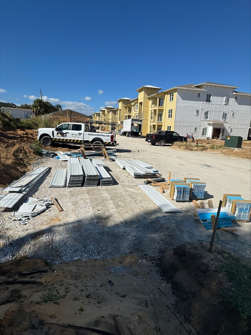 Metal roofing panels staged on site beside a Noland's truck at a multi-family construction project