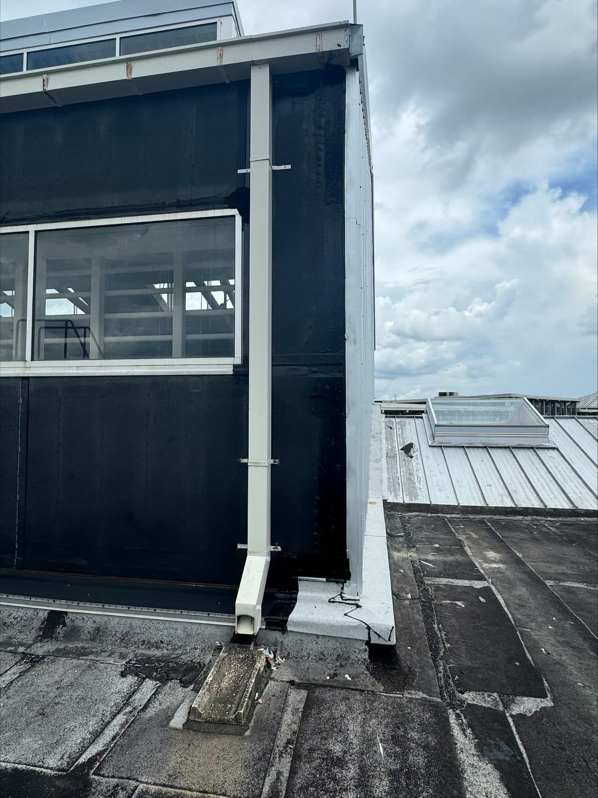 Commercial wall weatherproofed in black membrane with a new downspout before siding goes back on