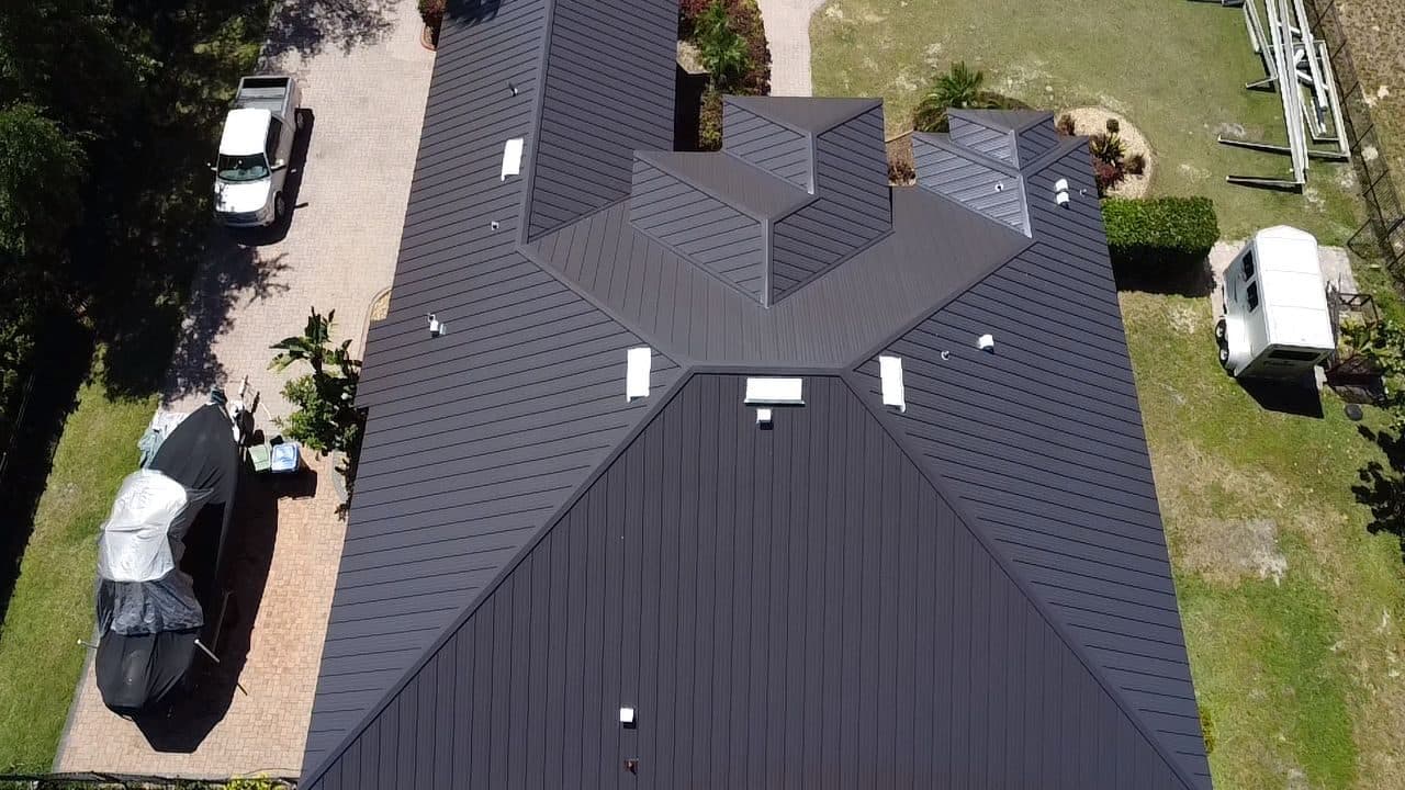 Aerial view of a completed dark bronze standing-seam metal roof on a residential property