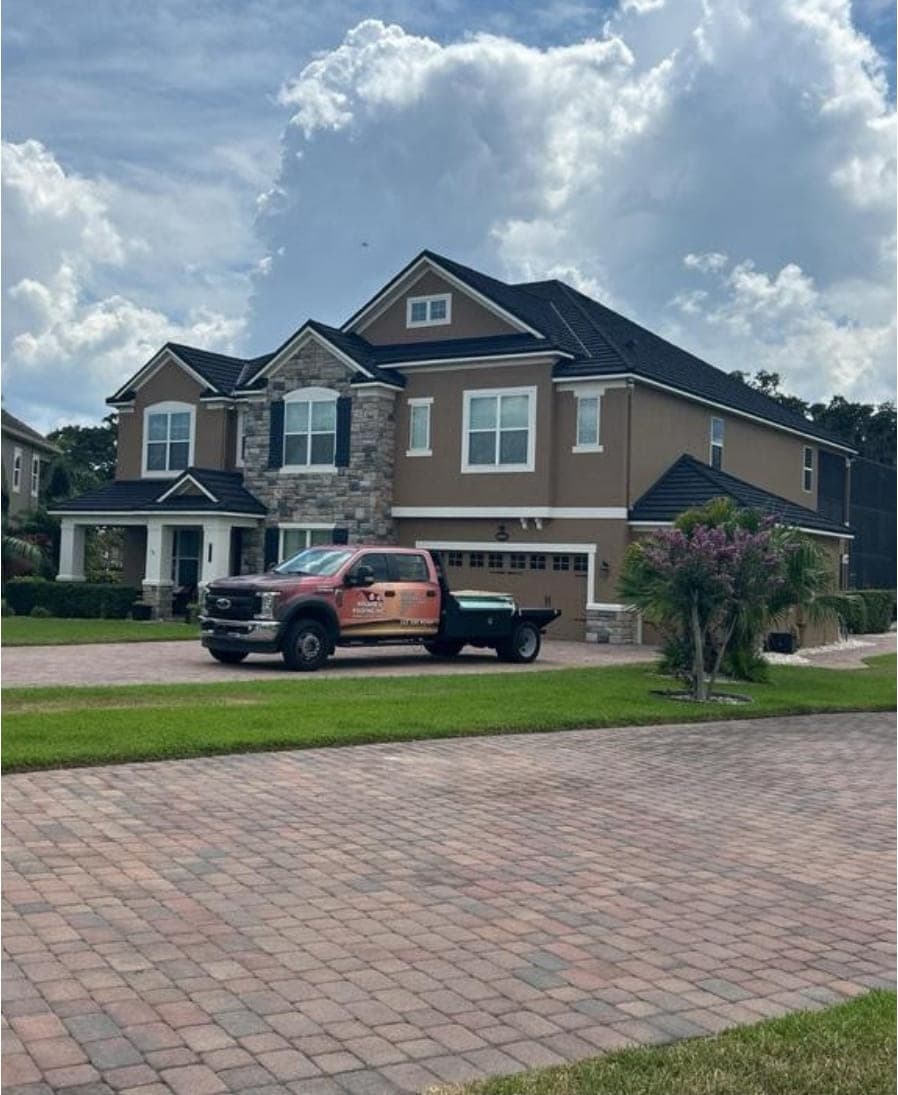 Winter Garden home with a stone-coated metal roof, stone accents and a paver driveway