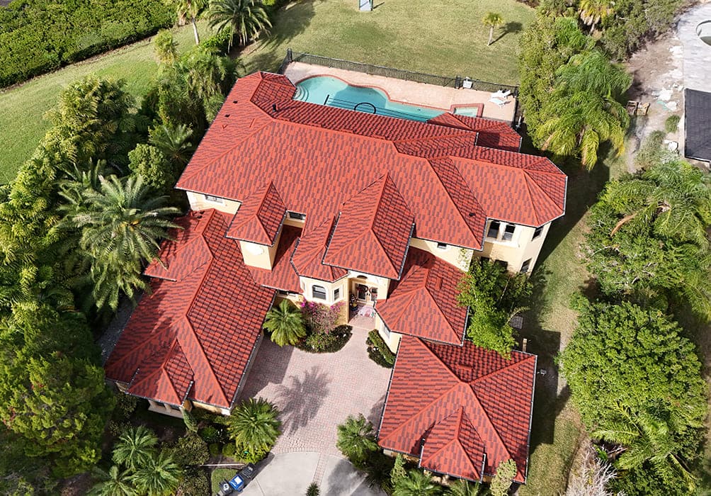 Aerial view of a blended red flat-profile tile roof on a two-story Florida home with a pool