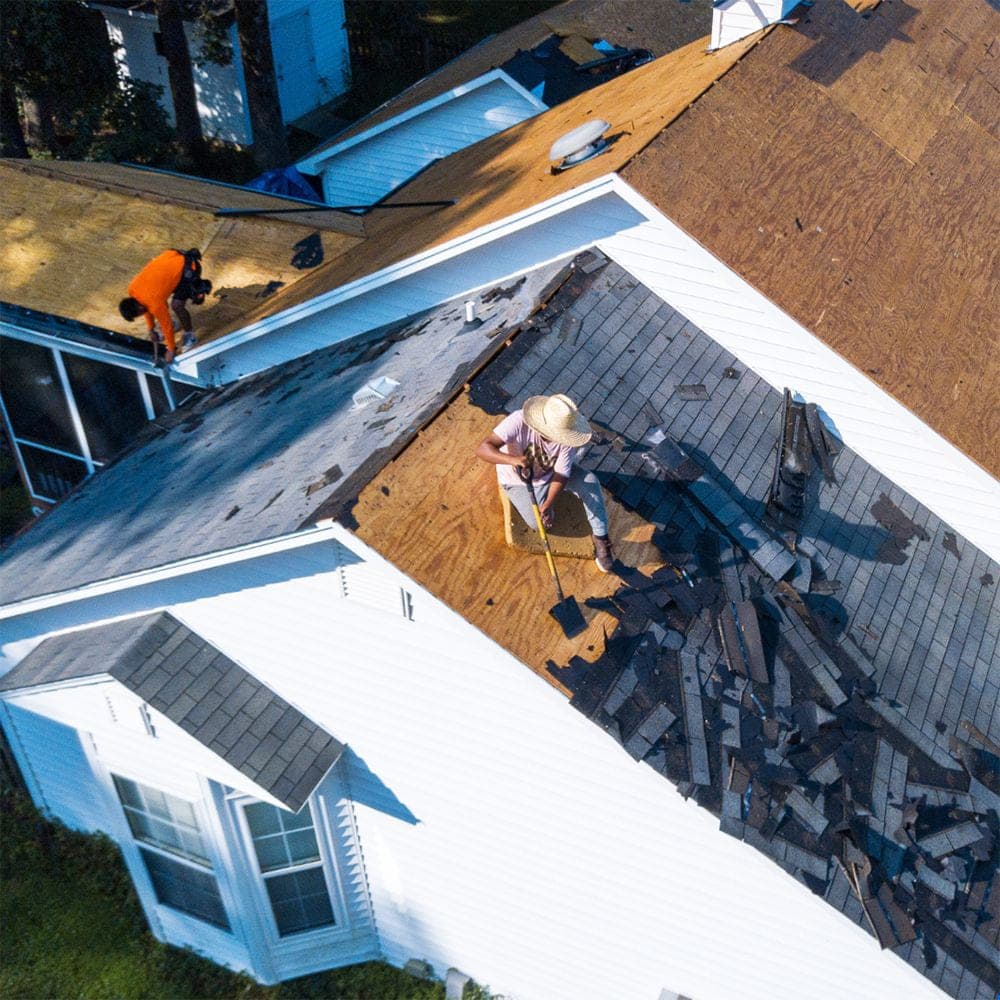 Aerial close-up of a tear-off in progress, old shingles stripped back to bare decking