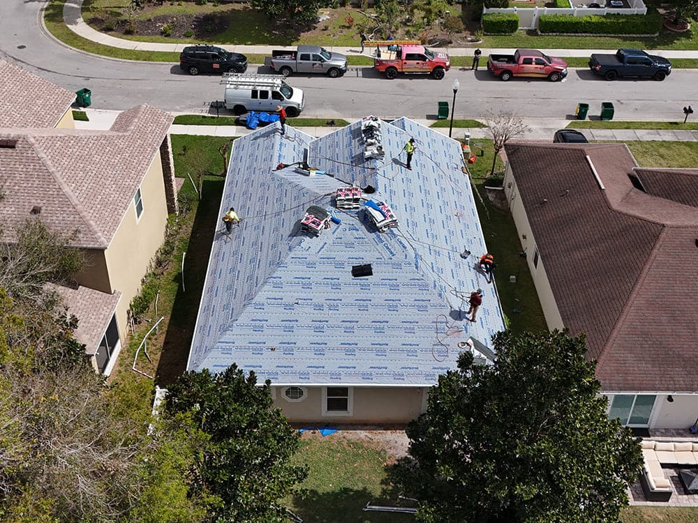 Aerial view of a roof with underlayment down and shingle bundles staged for installation