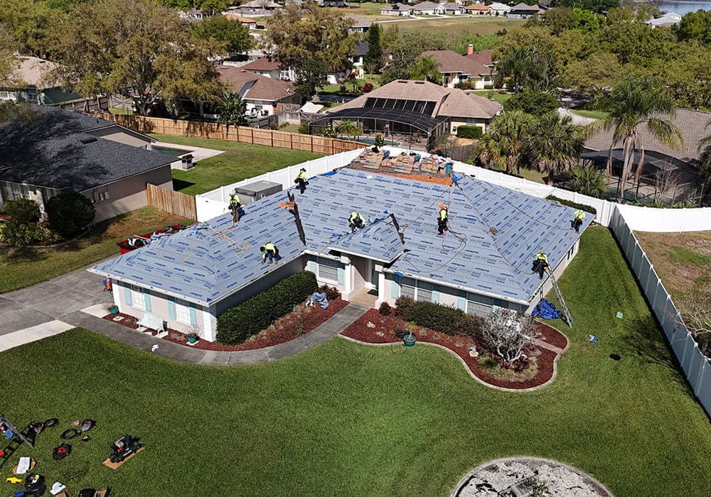 Aerial view of a Noland's crew installing synthetic underlayment across a roof deck