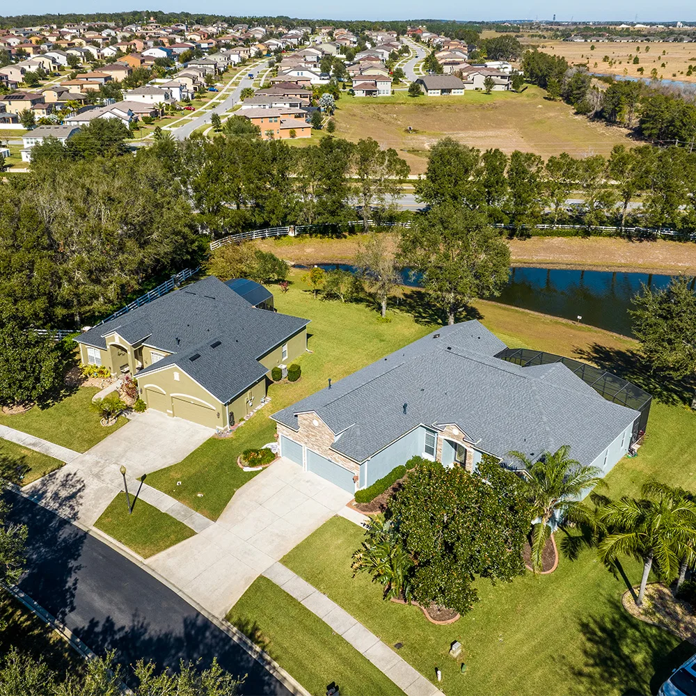 Aerial view of neighboring homes with gray shingle roofs, roof valleys, and vents.