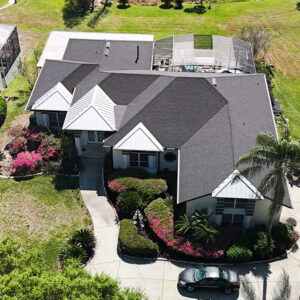 Aerial view of a residential neighborhood with a newly installed darkgrey shingle roof, showcasing a house with well-maintained landscaping.