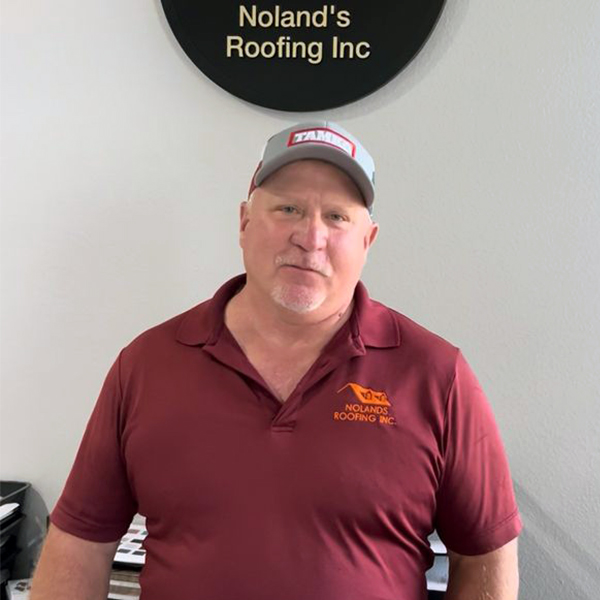 Headshot of Noland's Roofing employee Butch, taken in front of a white wall. Butch is wearing a Maroon Noland's Roofing branded polo.