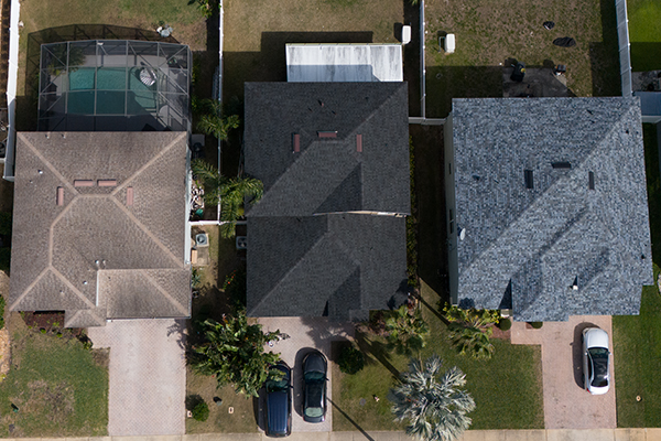 Aerial view of three neighboring residential roofs in Orange City, Florida, showcasing different shingle styles installed by Noland’s Roofing, trusted Orange City roofers for high-quality roof replacements.
