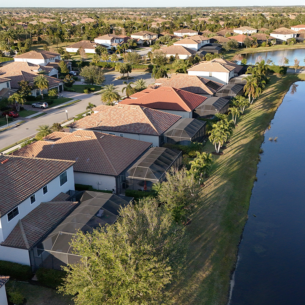 Aerial view of tile-roof homes along a canal in Bradenton, Florida, highlighting recent roof installations by Noland's Roofing—trusted Bradenton roofers.