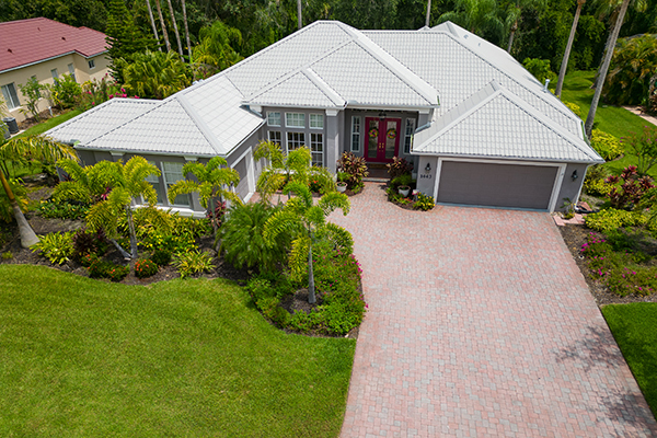 Elegant Florida home featuring a metal roof in Ascot White, professionally installed by Noland’s Roofing, surrounded by tropical landscaping and palm trees.