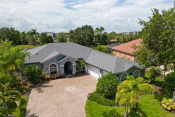 Front view of a residential home featuring a newly installed Silver Birch shingle roof by Noland's Roofing, showcasing clean lines, durable materials, and professional craftsmanship in a lush, tropical Florida setting.