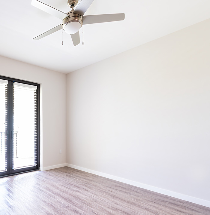 Empty living room with large window doors and white walls.
