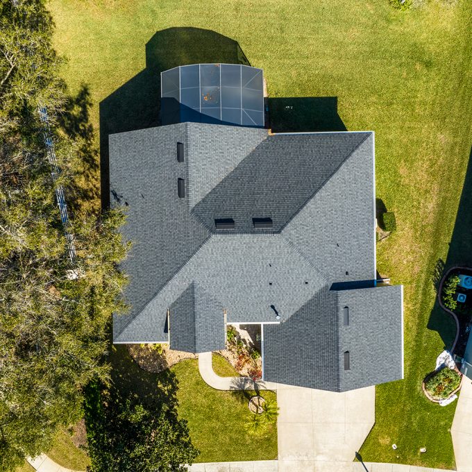 Drone shot of a brids eye view of a single family residential house with a gray shingle roof.