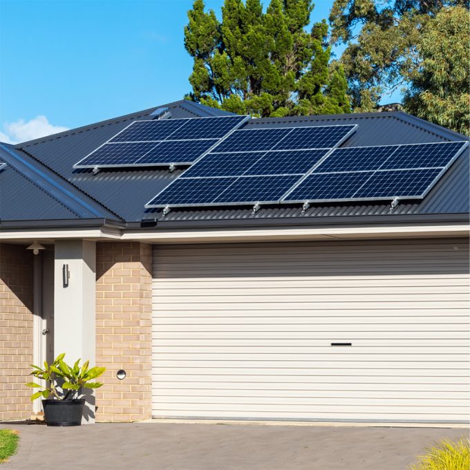 image of a single family residential home with solar panels on the front part of the roof above the garage
